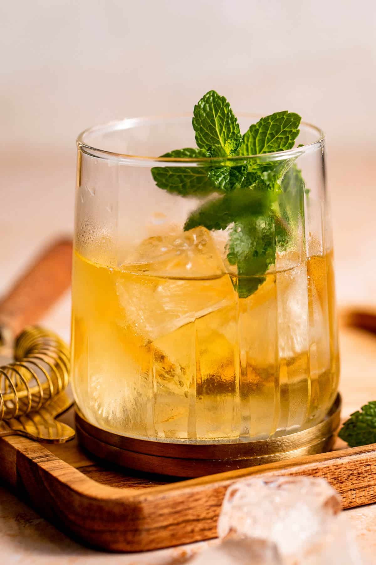 A Stinger Cocktail served with fresh mint on a wooden serving board.
