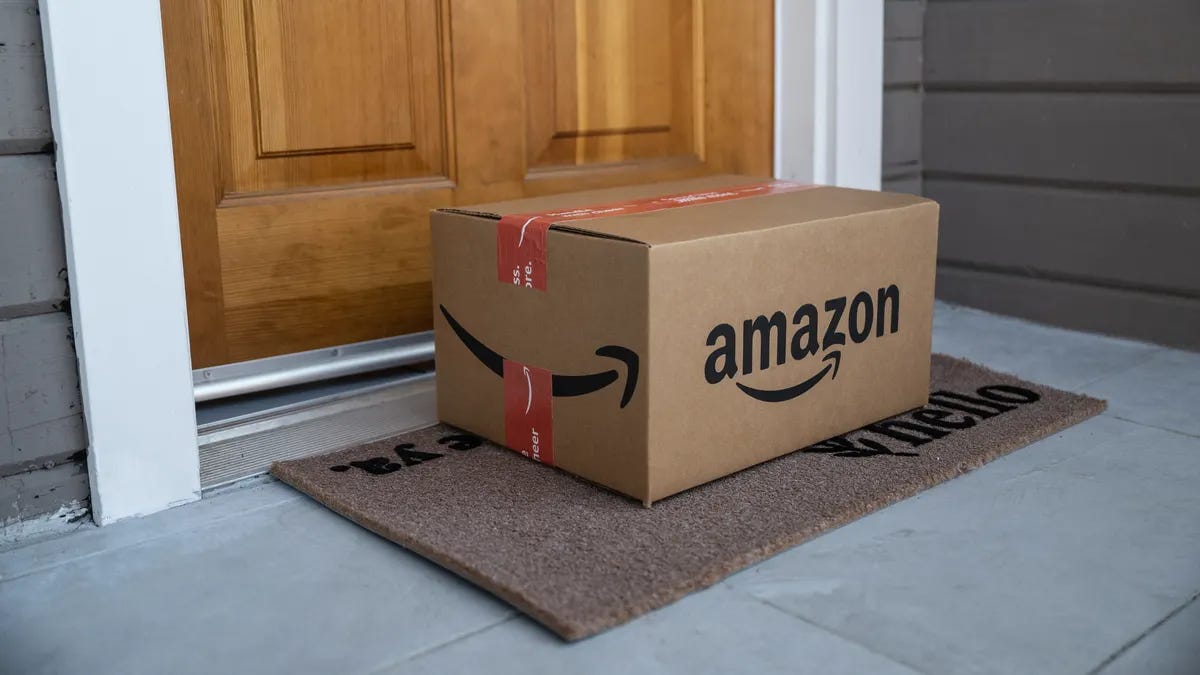 A large cardboard box sits on a welcome mat on the front porch of a house. A large cardboard box sits on a welcome mat on the front porch of a house.