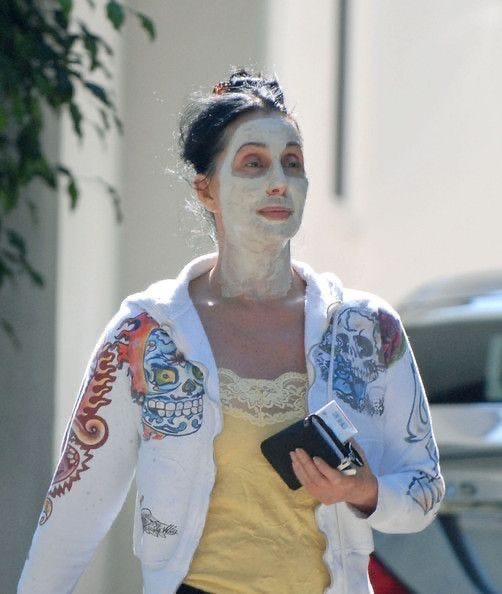 This may contain: a woman with white face paint walking down the street