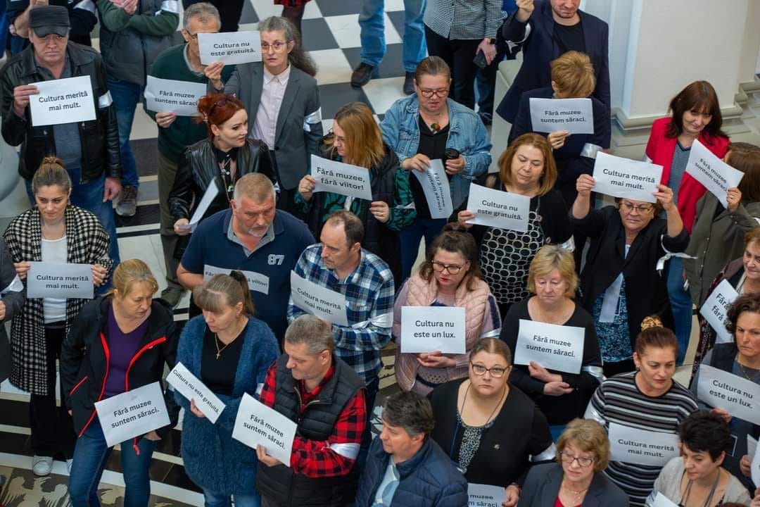 Protestatari dintr-un muzeu ce țin pancarte pe care scrie "Cultura nu este un lux" sau "Cultura nu este gratuită"