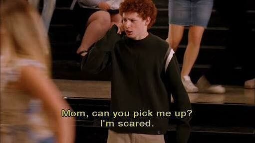 This may contain: a man talking on a cell phone while standing in front of some stairs with other people