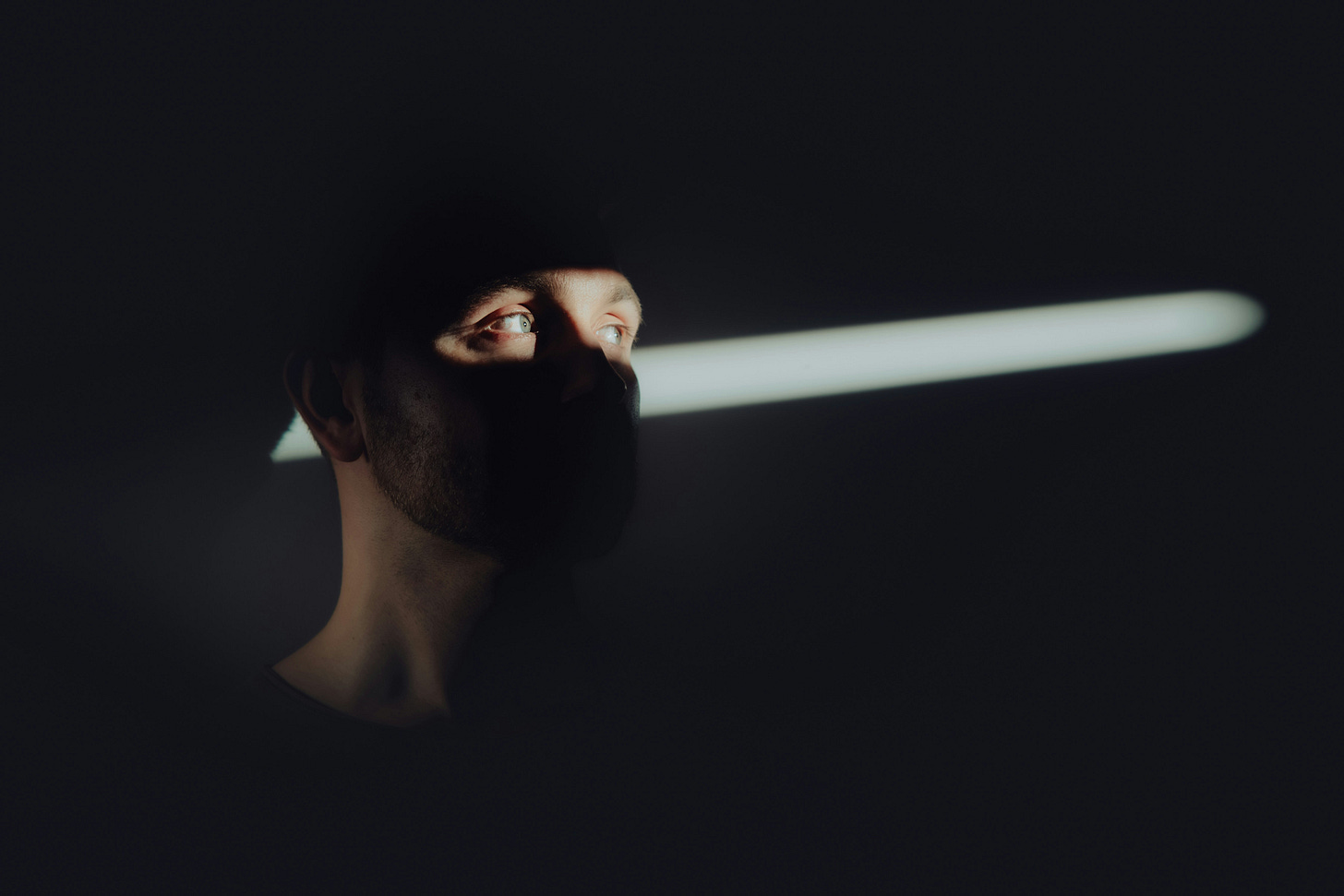 A man in a dark room. Light illuminates only his eyes. 