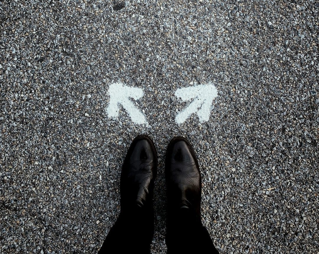 feet on asphalt between two directional arrows feet on asphalt between two directional arrows