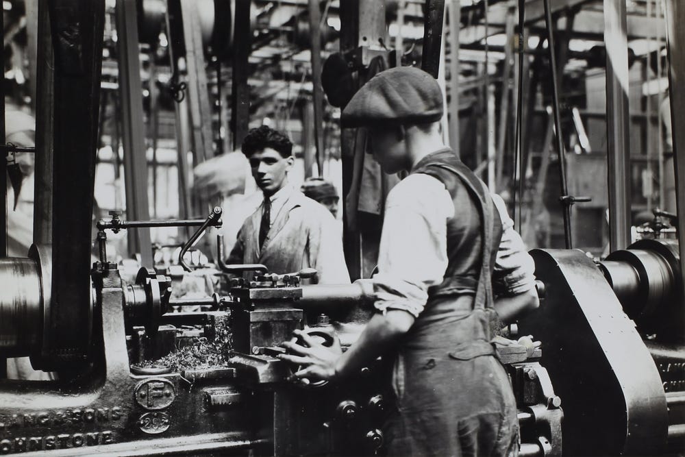 A black and white photograph of factory workers with no safety gear. A black and white photograph of factory workers with no safety gear.
