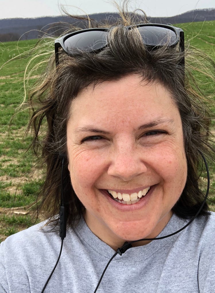 Image of Jen Dutrow, smiling, with shades on top of her head and earbuds in her ears. Image of Jen Dutrow, smiling, with shades on top of her head and earbuds in her ears.