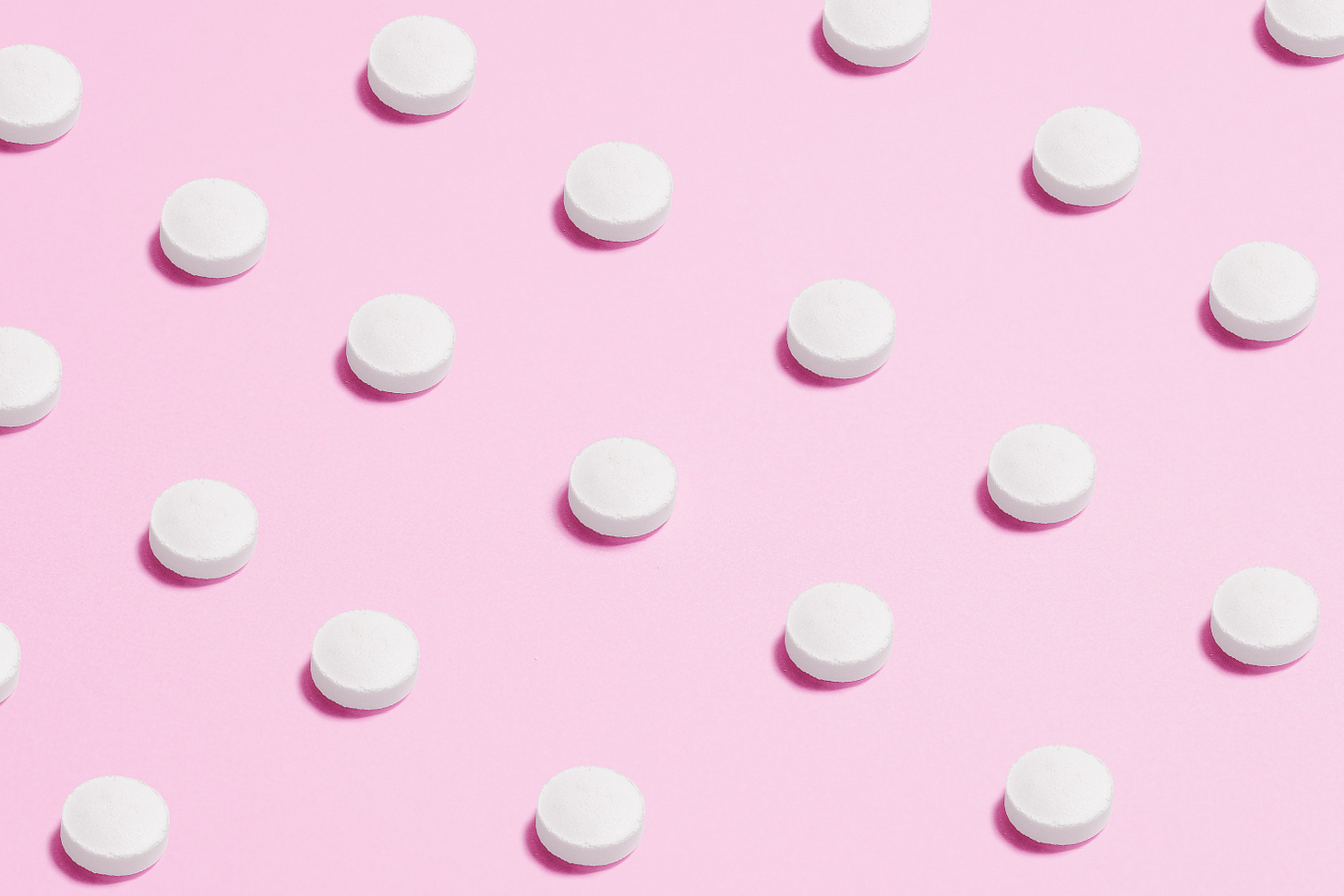 Equally distant pills on a pink background