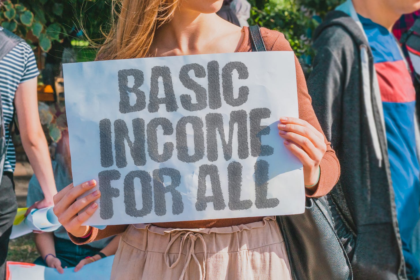 Woman holding sign, "Basic Income for All"