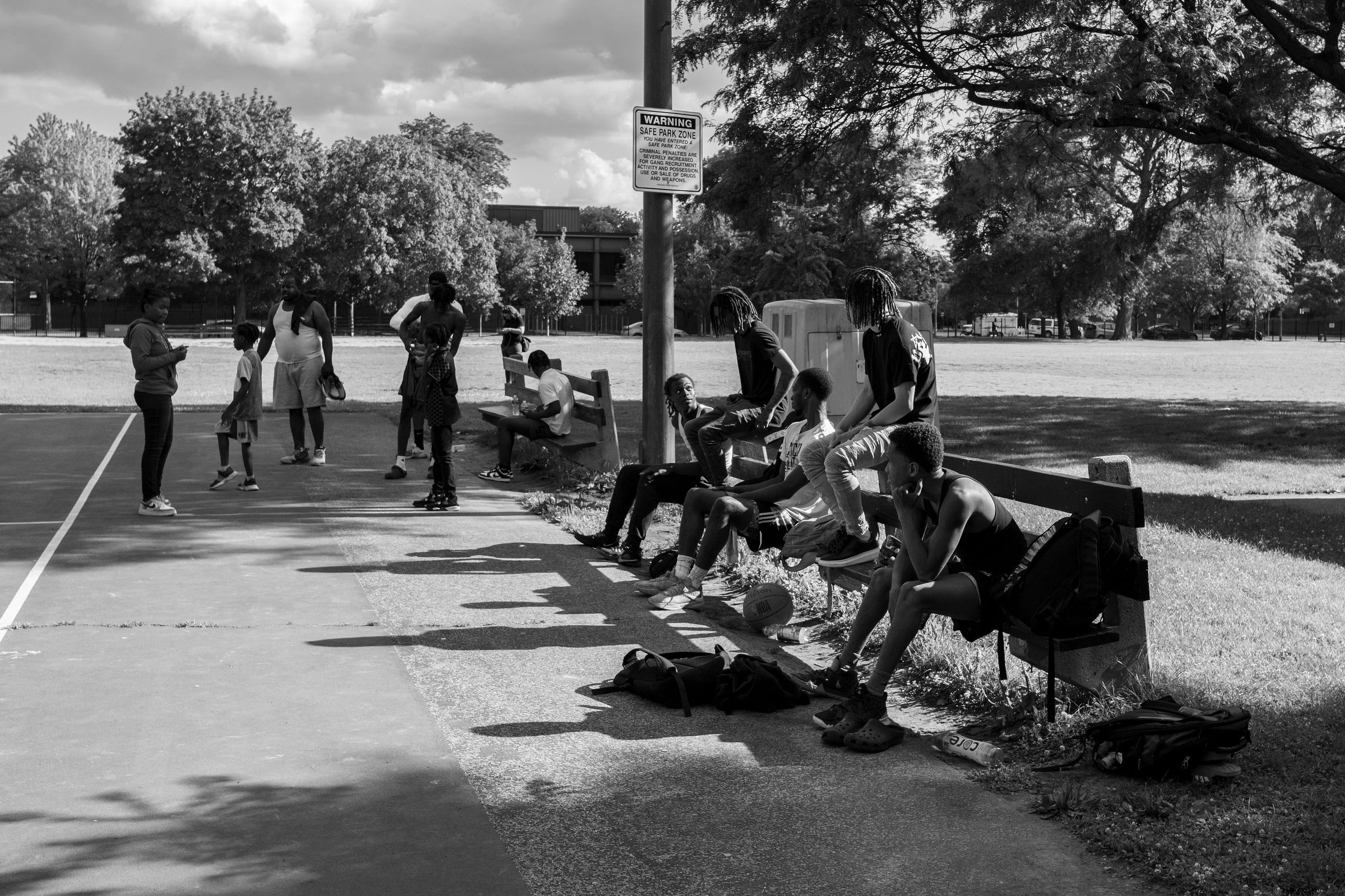 Black-and-white photo of people spending time at a basketball court.