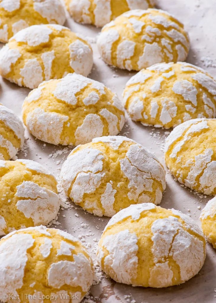 Gluten free lemon crinkle cookies on a lined baking sheet.