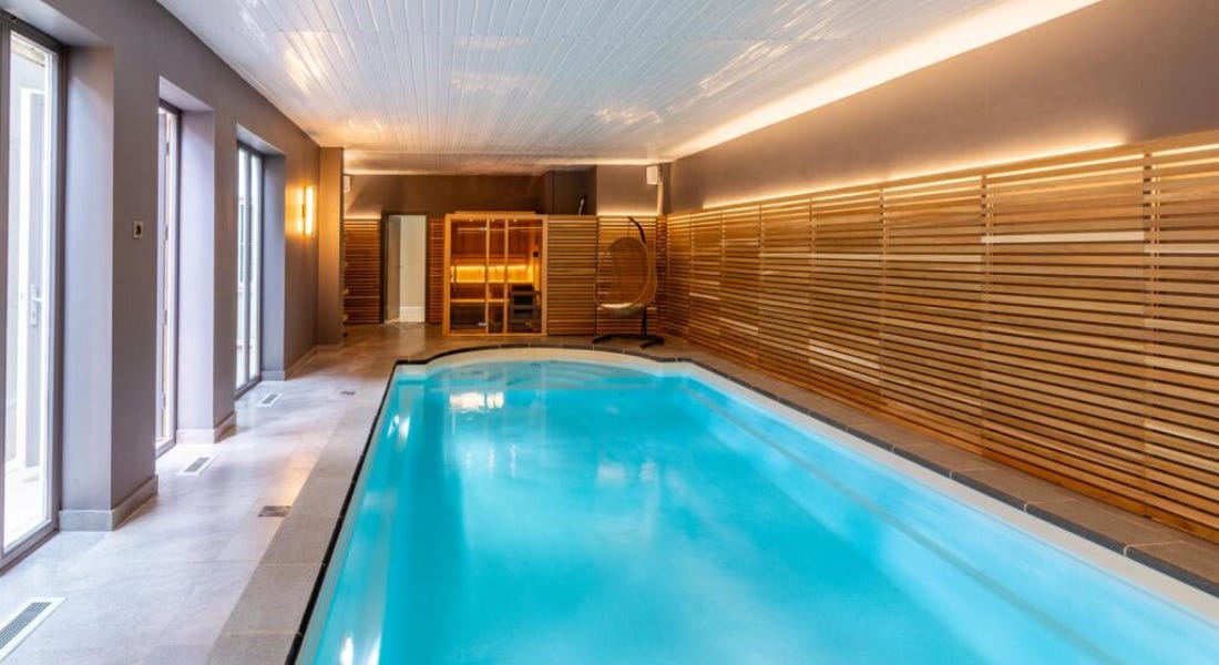 An interior with a swimming pool, wooden panelling, and grey walls An interior with a swimming pool, wooden panelling, and grey walls
