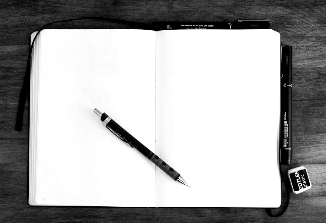 black and silver retractable pen on blank book