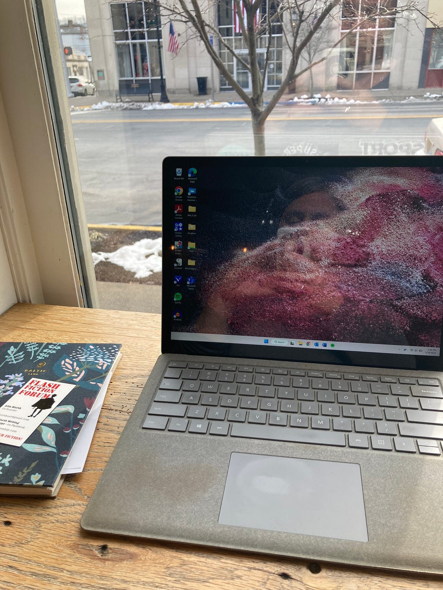 A computer sitting in a coffee shop window with a notebook beside it. A computer sitting in a coffee shop window with a notebook beside it.