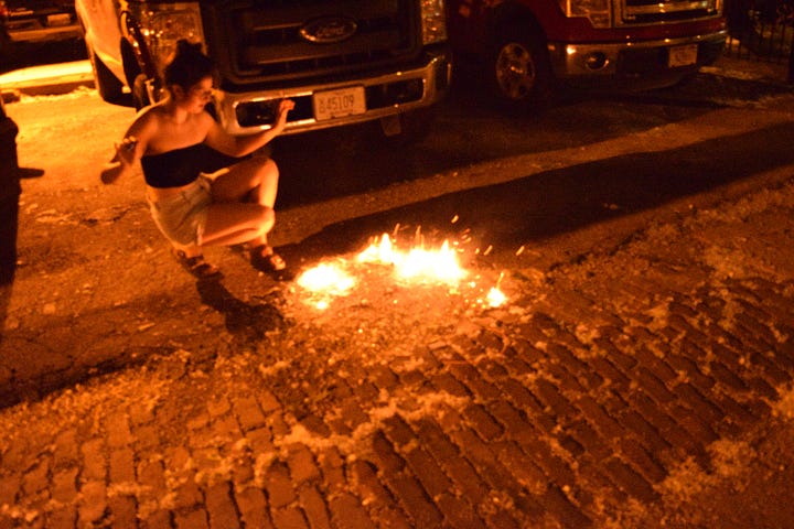 four photos of a young woman standing or crouching before burning poplar fluff in an alley