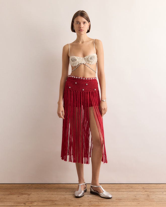 Woman in the Calder Fanni Fringe Skirt, featuring red fringe and a thigh slit, stands on a wooden floor against a plain wall—channeling the playful spirit of Calder’s Circus as seen at the Whitney Museum of American Art. Woman in the Calder Fanni Fringe Skirt, featuring red fringe and a thigh slit, stands on a wooden floor against a plain wall—channeling the playful spirit of Calder’s Circus as seen at the Whitney Museum of American Art.