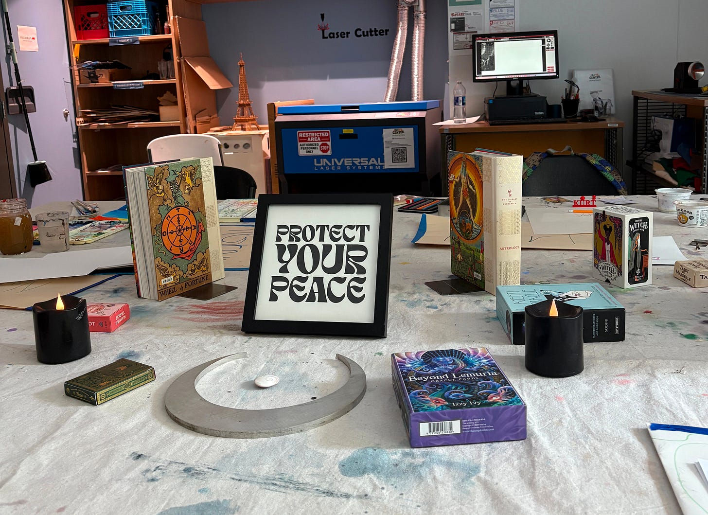 Tarot card decks laid out in a circle on a table covered with drop cloth. In the center is a print reading "protect your peace"