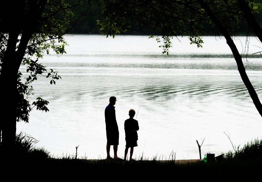 silhouette of couple standing near body of water during daytime silhouette of couple standing near body of water during daytime
