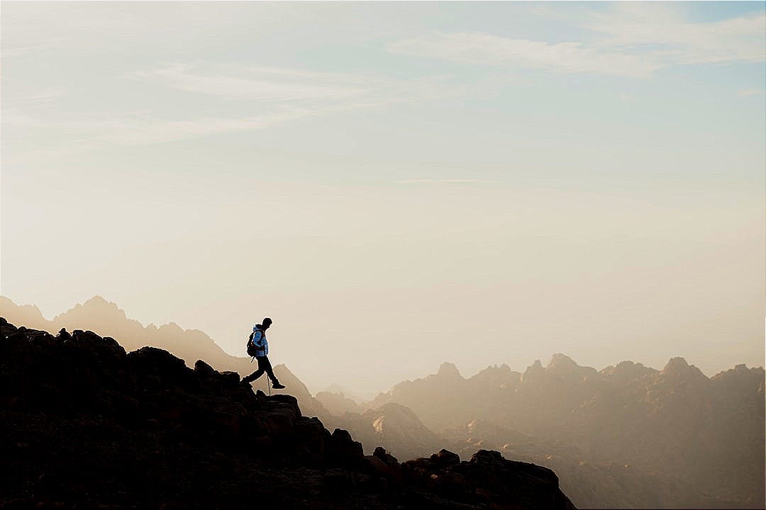 a man running up a mountain with a sky background