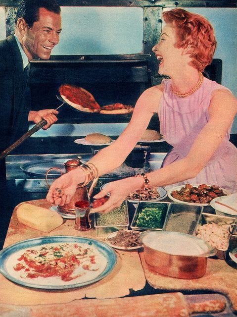 This may contain: a man and woman preparing food on a table