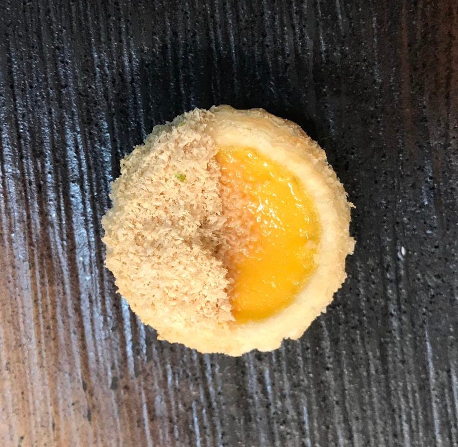 An overhead viewpoint of a egg custard tart on a dark slate background