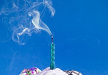 A cupcake with a birthday candle on it that has been blown out and is smoking slightly. A cupcake with a birthday candle on it that has been blown out and is smoking slightly.
