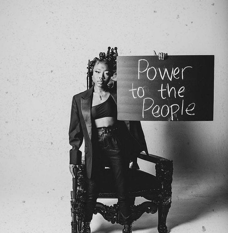 This may contain: a black and white photo of a woman sitting in a chair holding a sign that says power to the people