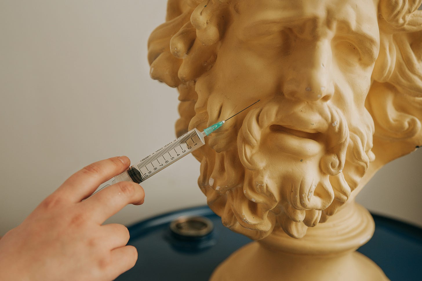 man sticking a needle onto face of a wrinkly statue