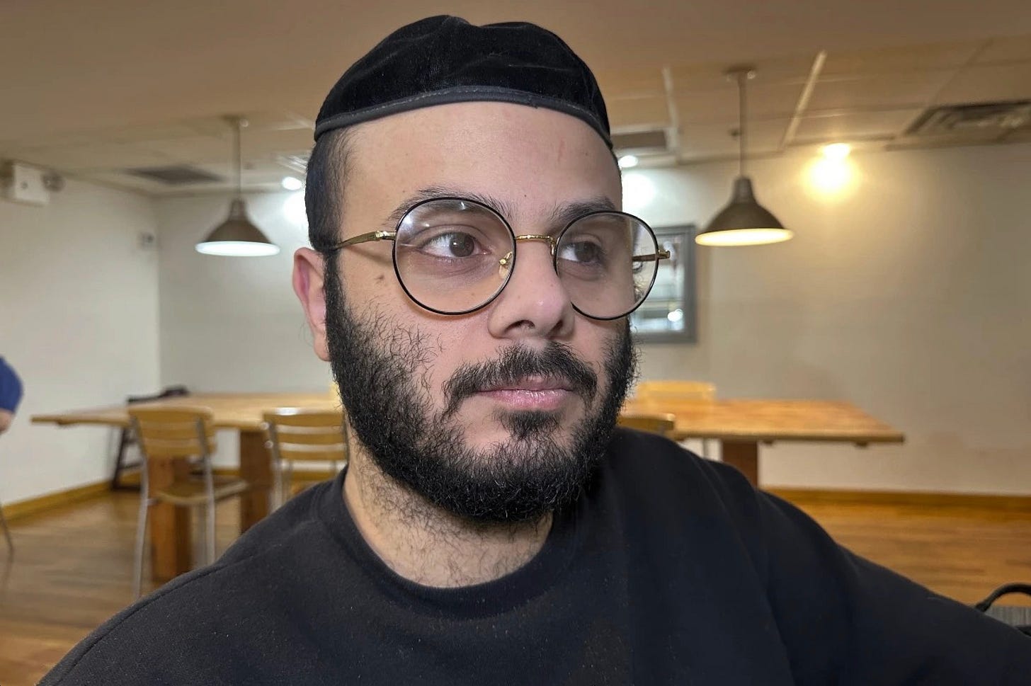 A person wearing glasses and a black hat

AI-generated content may be incorrect.
