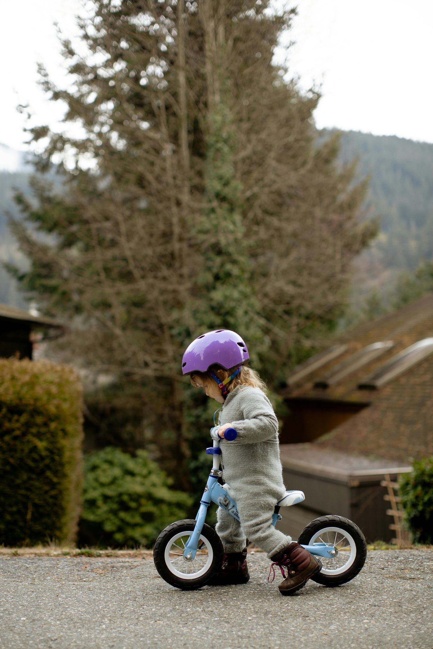 Small child walks a strider bike with concentration