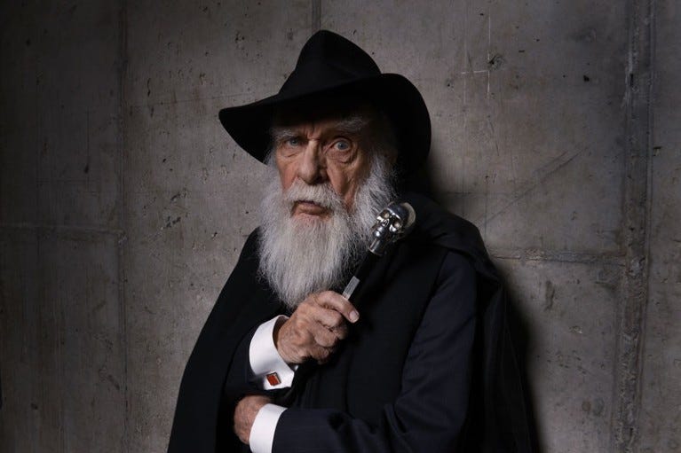 James Randi poses for a portrait against a concrete wall wearing a black brimmed hat and holding a cane with a skull topper James Randi poses for a portrait against a concrete wall wearing a black brimmed hat and holding a cane with a skull topper