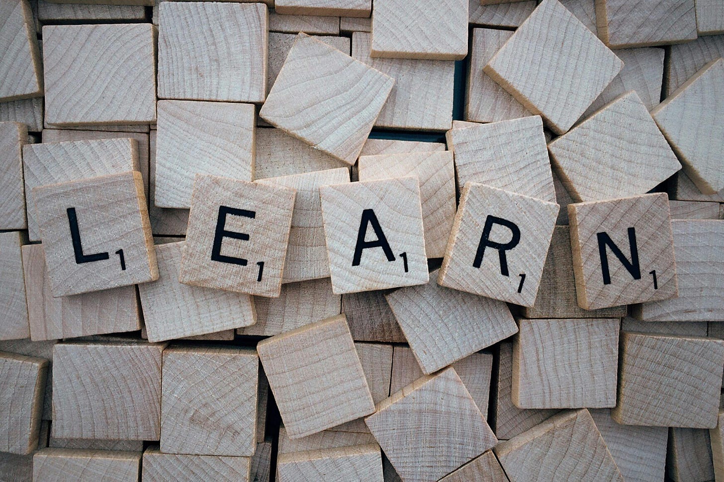 “LEARN” spelled out in wooden Scrabble tiles.