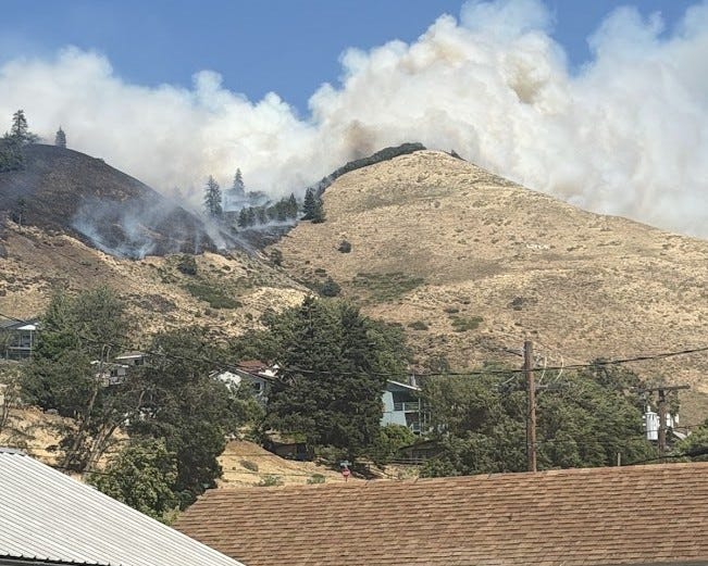 Large plumes of smoke rising from the Lyle Hill Fire burning on the hillside above homes in Lyle, Washington, seen from town.