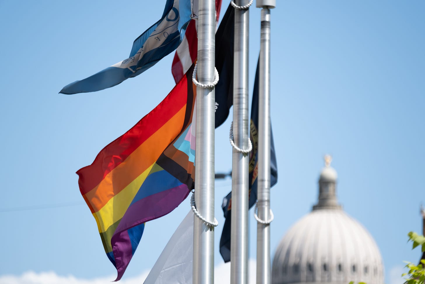 A Pride flag, a U.S. flag, an Idaho flag and an organ donation flag fly in front of Boise City Hall in Idaho.  