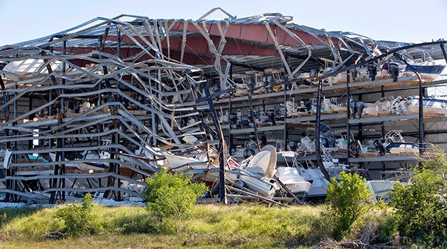 Photos of front and side views of a damaged boat storage facility and mangled boats, damaged by Hurricane Harvey. Image source: Inge Spence/Alamy Images, taken November 2017.
