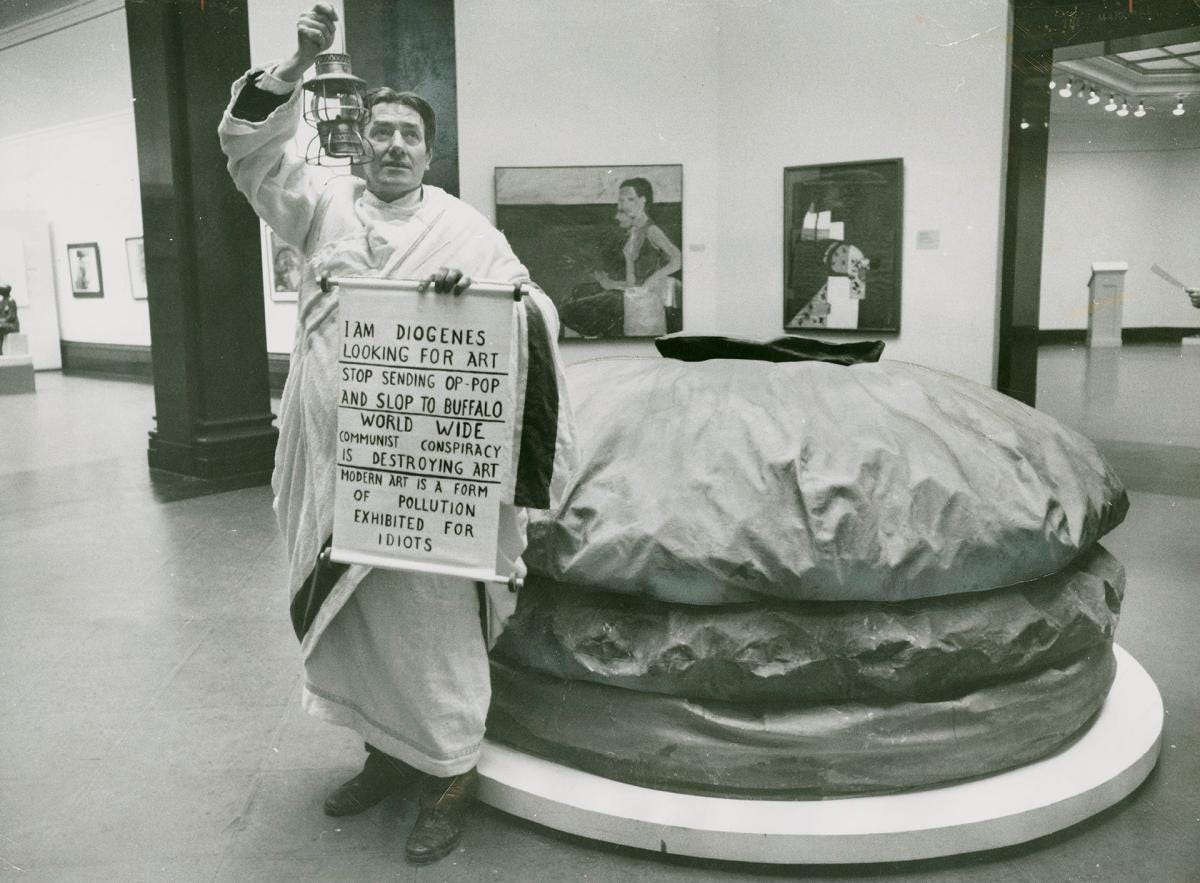 Desperate as Diogenes / Diogenes, ancient Greek who carried a lantern searching for an honest man, is imitated by Louis Dlugosz from Lackawanna, N.Y., as he pickets Claes Oldenburg's Giant Hamburger sailcloth sculpture in Art Gallery of Ontario Desperate as Diogenes / Diogenes, ancient Greek who carried a lantern searching for an honest man, is imitated by Louis Dlugosz from Lackawanna, N.Y., as he pickets Claes Oldenburg's Giant Hamburger sailcloth sculpture in Art Gallery of Ontario