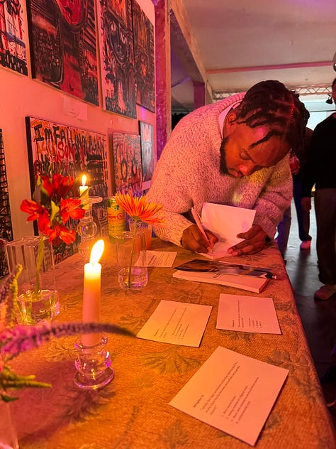 pictures of author signing book at book launch event, and aesthic placement of candles, dim light, and books displayed in accordion style
