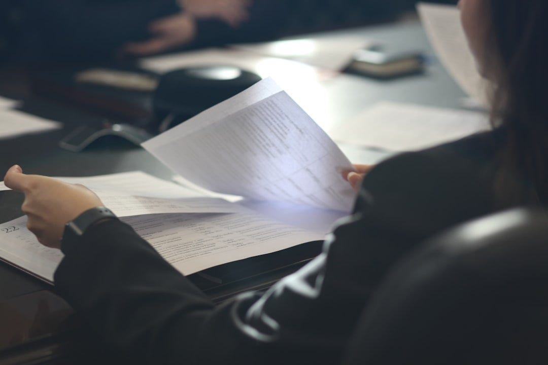 a woman sitting at a table reading a paper a woman sitting at a table reading a paper