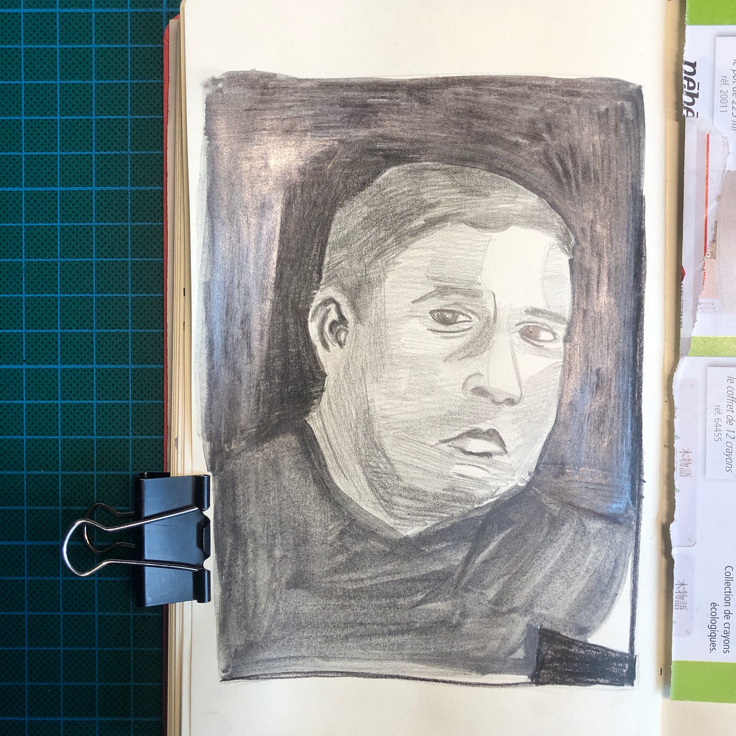 Photo de la page de mon sketchbook où j'ai réalisé le dernier portrait. Il s'agit d'un portrait d'homme réalisé avec plusieurs valeurs de crayons graphite.
