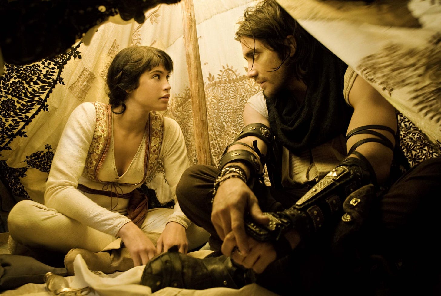 Gyllenhaal and Arterton in period costume sitting in a tent.