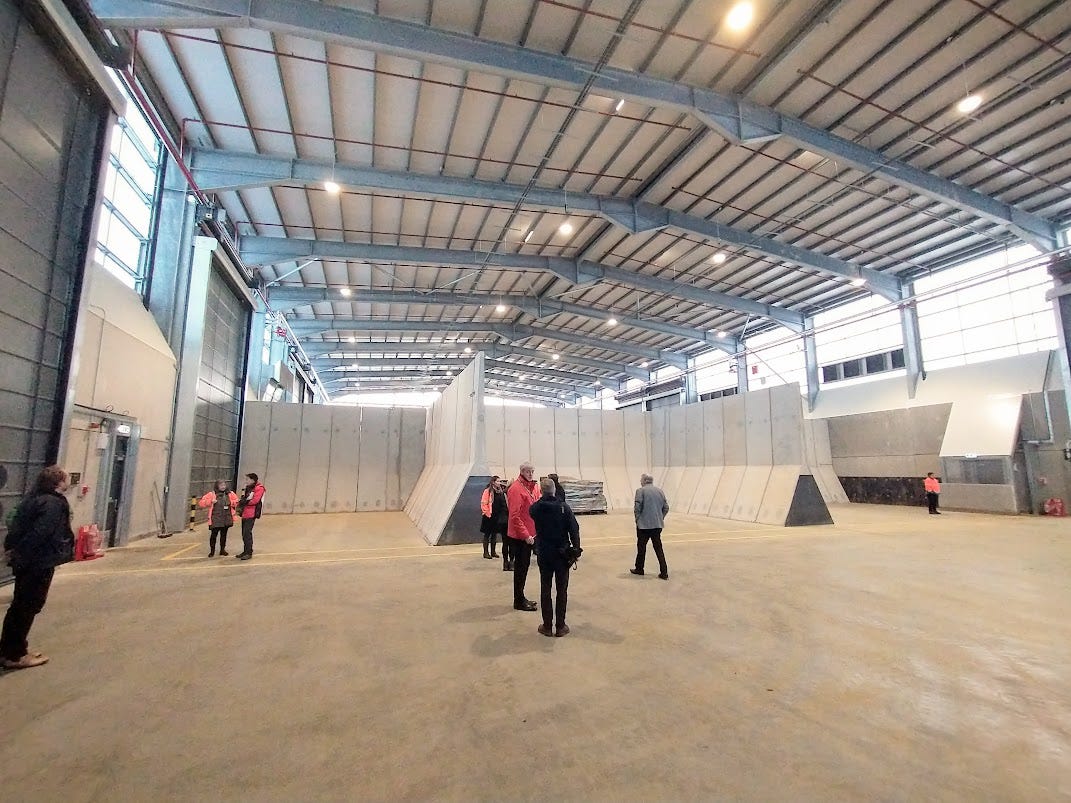 Inside the huge shed. People looking around at the concrete bays
