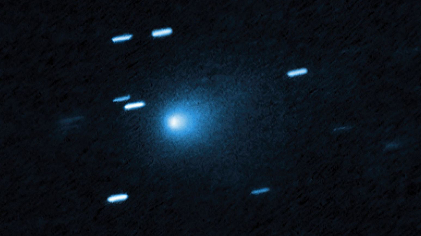 A blue ball of light shines between streaks of blueish light from stars in outer space