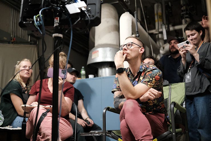 A director on the set of a short film watching a monitor intently. A director on the set of a short film watching a monitor intently.
