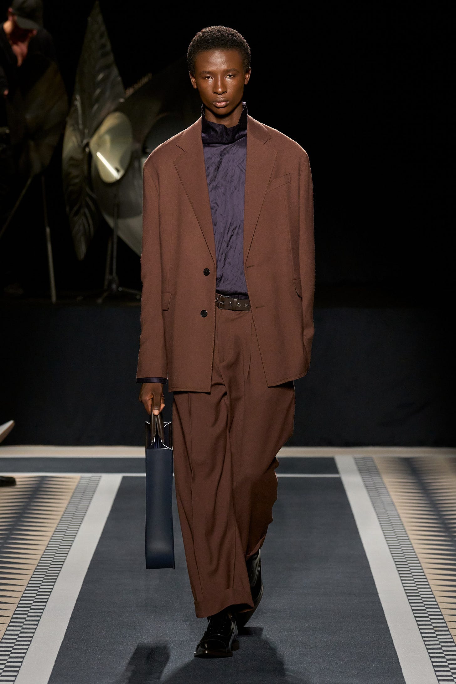 Image may contain Clothing Coat Fashion Adult Person Footwear Shoe Accessories Belt Formal Wear Suit and Standing