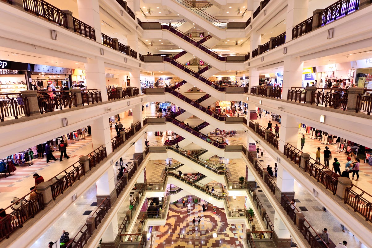 A huge. multi-level mall with white walls, bright eyes, and tons of people