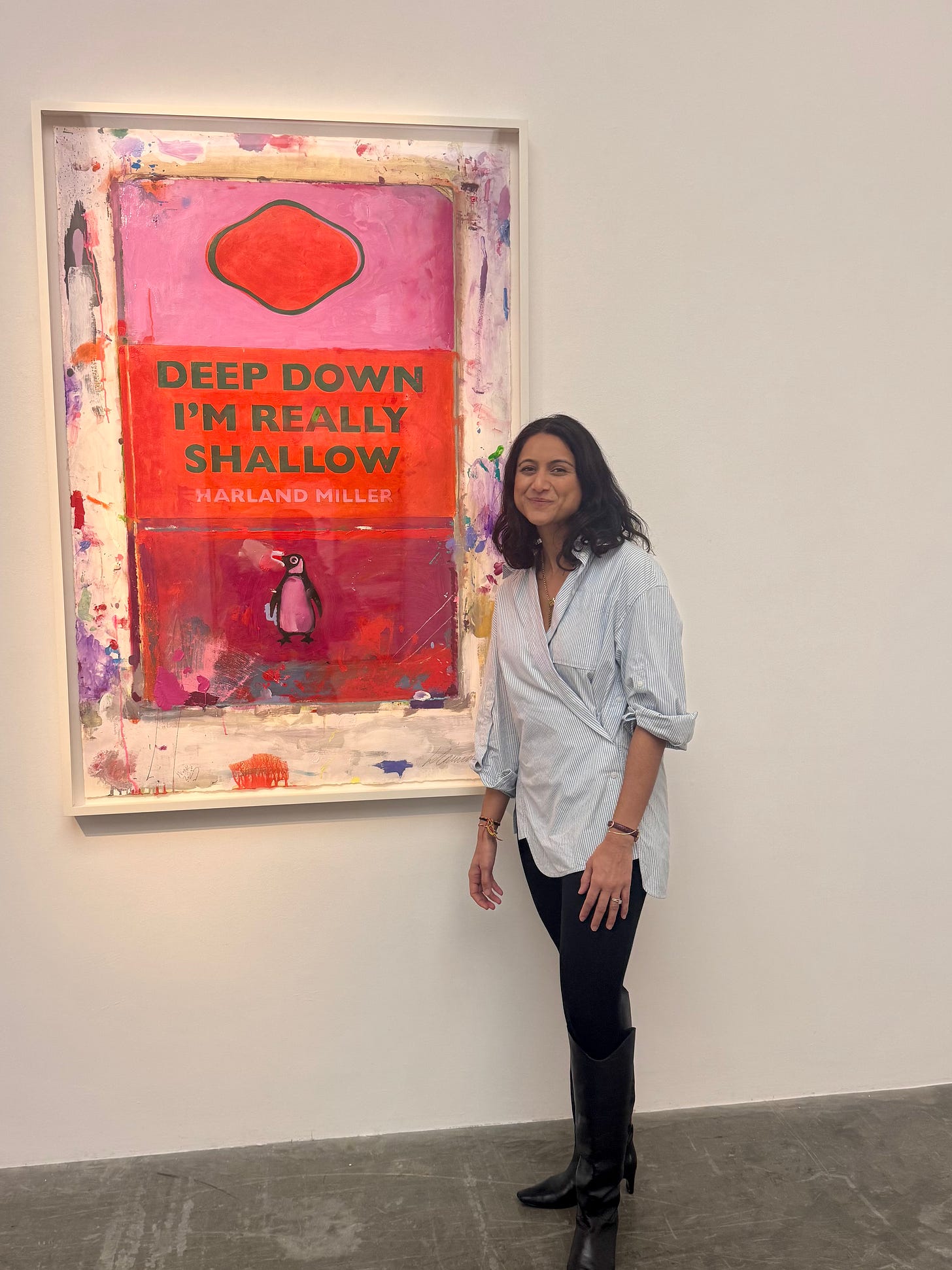 Anar standing beside Harland Miller’s large pink, red, and orange text-based painting Deep Down I’m Really Shallow at White Cube in London.