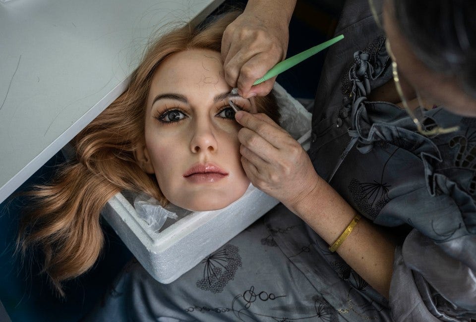 A worker adds hair to a silicone sex doll's head in a factory.
