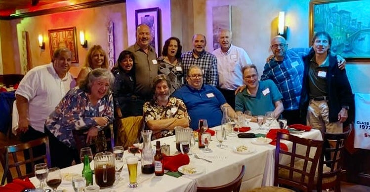 Photo of a group of men and women posing at a restaurant table after a dinner