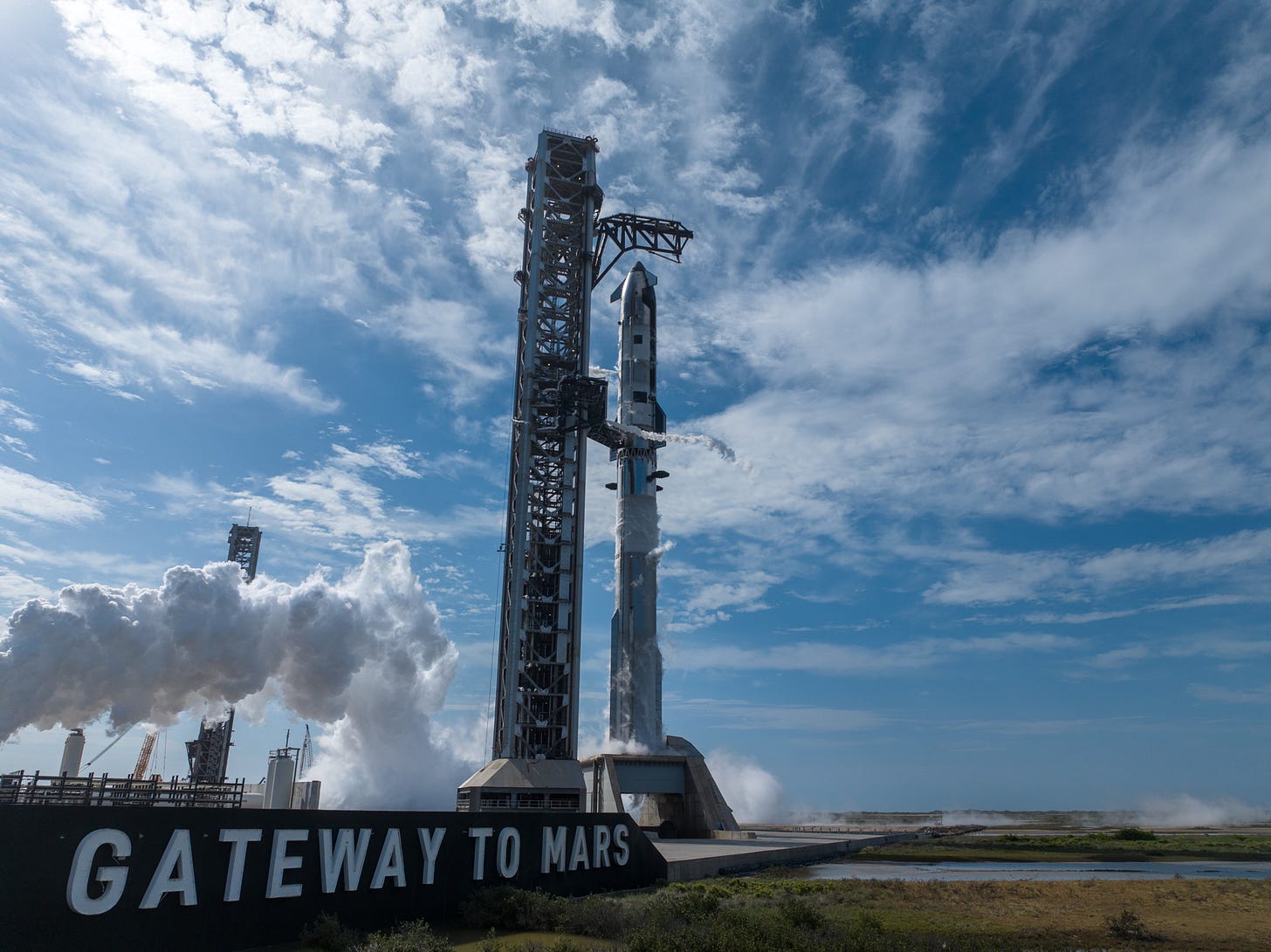 a big silver and black rocket on a launch pad next to a sign reading "Gateway to Mars"