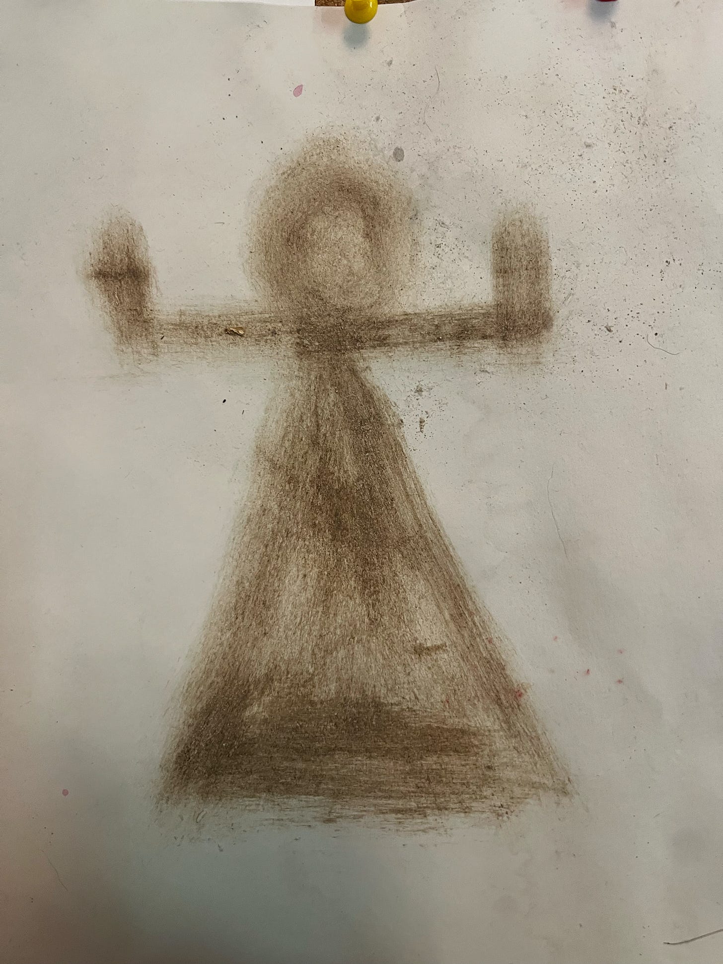 A symbol of the goddess Tanit drawn in brown soil on paper: a circle atop a triangle with a horizontal line between them, bent up on both ends, like a simple representation of a woman with her arms raised to the sky
