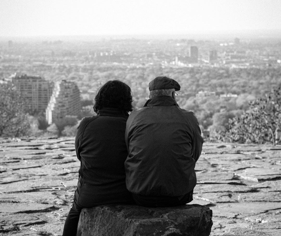 a couple of people sitting on top of a rock