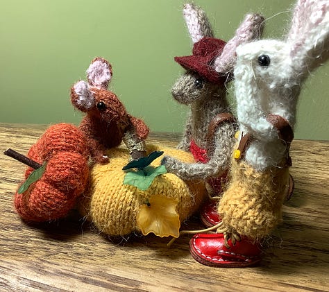 Two rabbits looking at two pumpkins, and a tiny rabbit head poking out. The bigger rabbits look shocked.